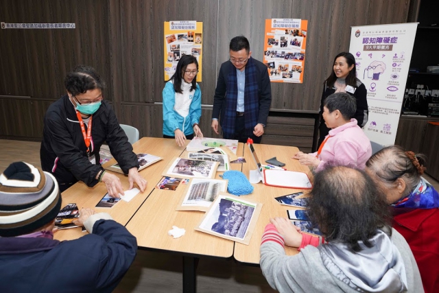 渠務署行政助理徐泳雯女士向發展局政治助理馮英倫先生介紹渠務署義工隊為長者製作的西環舊照拼圖與彈珠盤