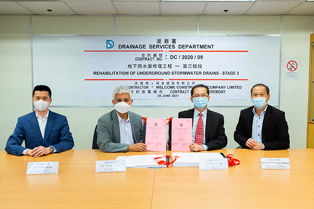 渠務署助理署長/操作維修何耀光先生（右二）及首席項目統籌/策劃及復修陳志明先生（右一）與偉金建築有限公司董事陳詩坪先生（左二）及董事黃志輝先生（左一）進行合約簽署儀式